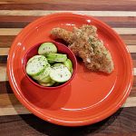 air fried chicken finger on an orange plate with a side dish of zucchini
